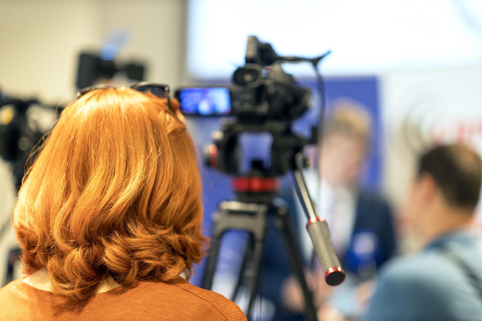 A camera operator filming a local news segment in a small studio